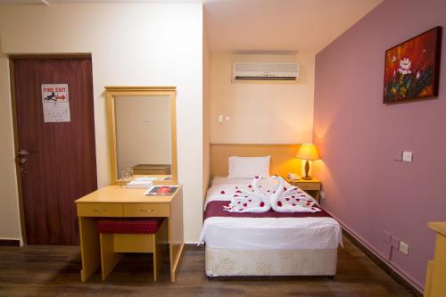a bedroom with a bed and a sink and a mirror at Mutrah Hotel in Muscat