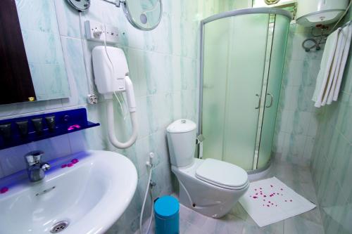 a bathroom with a shower and a toilet and a sink at Mutrah Hotel in Muscat