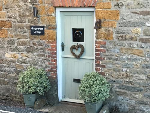 a white door with a heart wreath on it at Gingerbread Cottage in Chideock