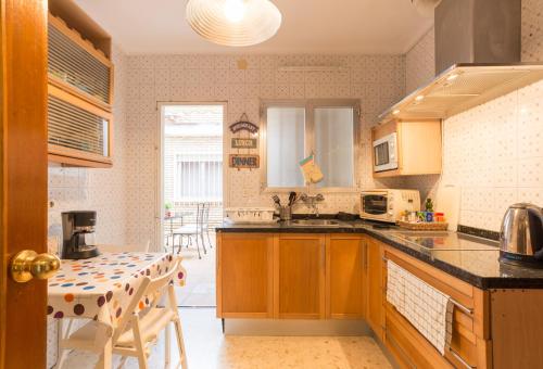 una cocina con armarios de madera y una mesa. en Rafaela Guest House, en Málaga