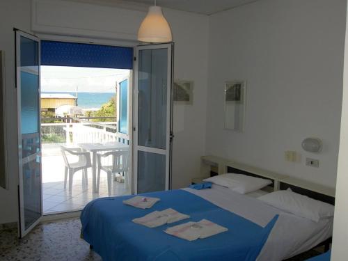 a bedroom with a bed and a balcony with a table at Baia del Sole in Paestum