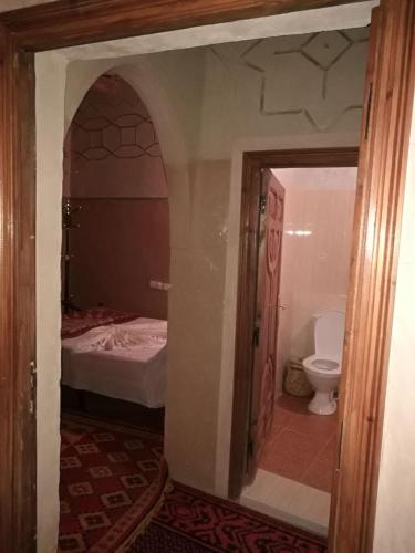 a bathroom with a bed and a toilet in a room at Riad Berbère Boutaghrar in Bou Drarar