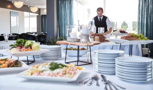 a man standing in front of a table with plates of food at Skaga Hotel in Hirtshals