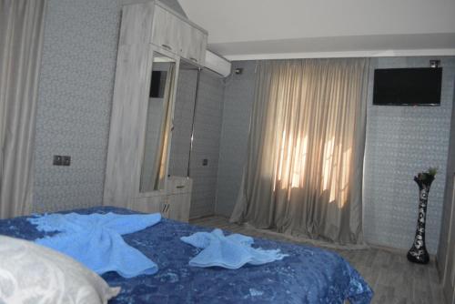 a bedroom with a bed with blue sheets and a window at Golden Way in Tbilisi City