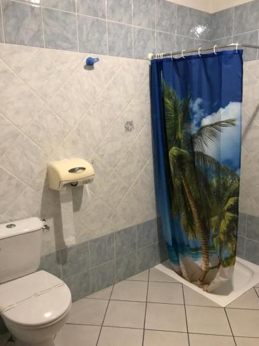 La salle de bains est pourvue de toilettes et d'un rideau de douche avec un palmier. dans l'établissement Hôtel Vesuvio, à Lourdes