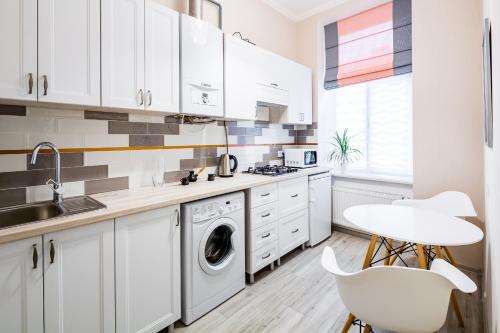 a kitchen with white cabinets and a washer and dryer at Old Town Cosy Apartment in Lviv
