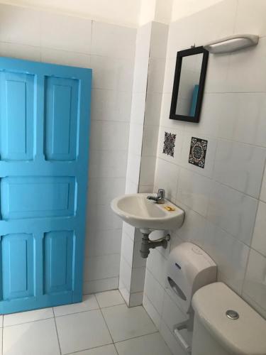 baño con lavabo y aseo y puerta azul en Hostal 1811, en Cartagena de Indias