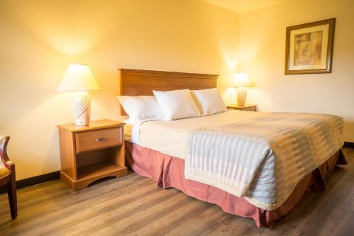 a hotel room with a bed and two night stands at Sunnyside Inn and Suites in Clackamas