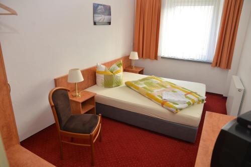 a bedroom with a bed and a chair and a window at Haus Sankt Florian in Halberstadt