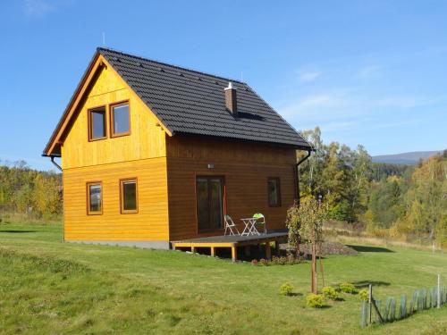 a yellow house with a black roof on a field at Chata Karamelka in Dolní Moravice