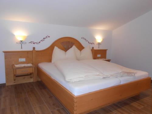 um quarto com uma cama de madeira com lençóis e almofadas brancos em Gollehenhof em Sankt Johann im Pongau