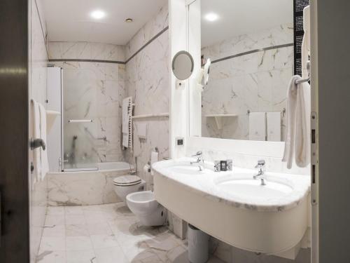 a white bathroom with a sink and a toilet at Hotel Milano in Padova