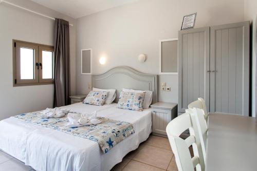 a bedroom with a white bed and a table and chairs at Mythos Suites Diskos in Léntas