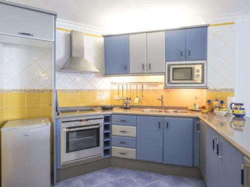 a kitchen with blue cabinets and a microwave at Apartamento Mar y Sol in Puerto de la Madera