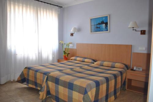 a bedroom with a bed with a blue and yellow striped blanket at Felipe II in Peñíscola