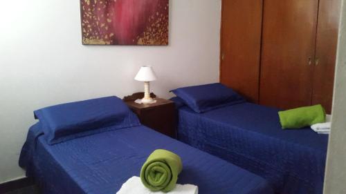 2 camas en una habitación con sábanas azules y sombrero en Dpto San Martin en Salta