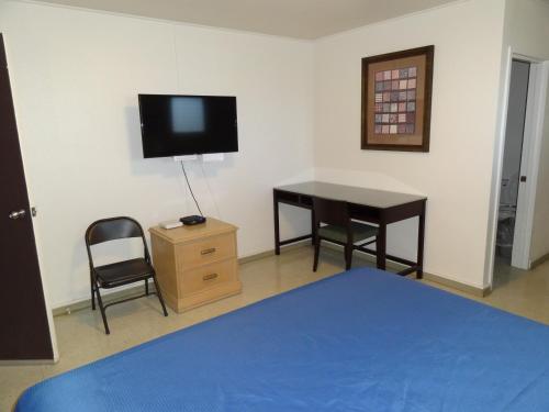 a bedroom with a desk and a tv and a bed at Tip Top Motel in Lihue