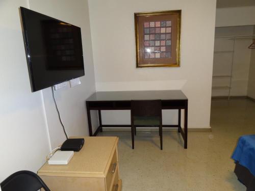 a room with a desk and a television and a table at Tip Top Motel in Lihue