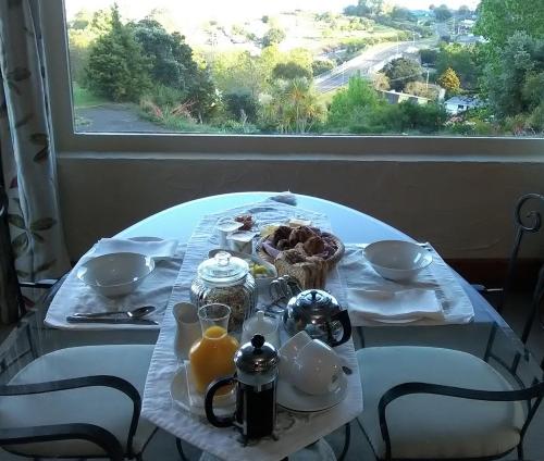 a table with breakfast food on it with a window at La Casa Te Puru Lodge in Te Puru