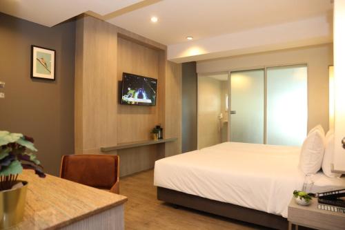 a hotel room with a bed and a tv at Miracle Suvarnabhumi Airport in Lat Krabang