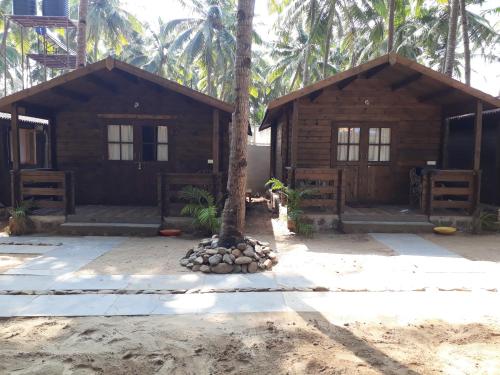 a wooden cabin with a palm tree in front of it at Agonda Paradise in Agonda