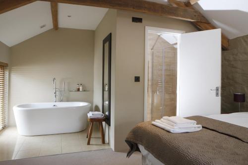 uma casa de banho com uma banheira, uma cama e um chuveiro em The Lamb Inn em Crediton