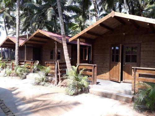 a wooden cabin with palm trees in front of it at Agonda Paradise in Agonda