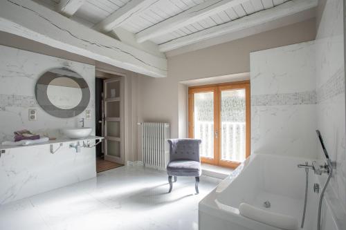 La salle de bains blanche est pourvue d'une chaise et d'un lavabo. dans l'établissement La Barbotiere, à Chevannes