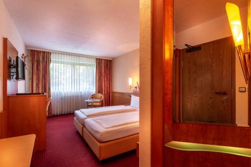 a hotel room with a bed and a mirror at Hotel Zum Rosengarten in Darmstadt