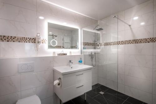 a white bathroom with a sink and a mirror at Hotel Zum Rosengarten in Darmstadt