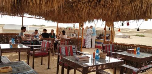a group of people sitting at tables in a restaurant at Legend Desert camp in Fulayj al Mashāʼikh