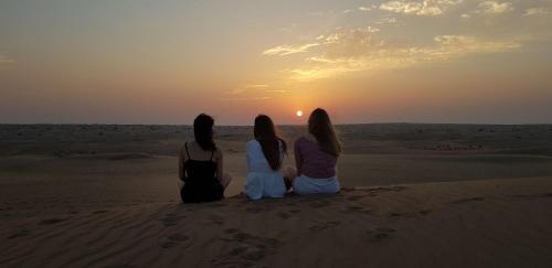 two women sitting on the beach watching the sunset at Legend Desert camp in Fulayj al Mashāʼikh