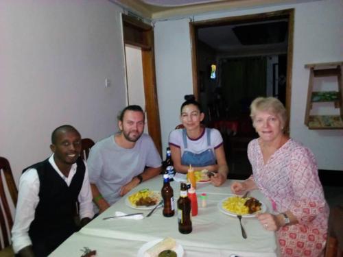 a group of people sitting around a table with food at Rena Akasha Establishments in Kyenjojo