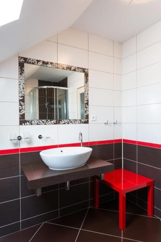 a bathroom with a white sink and a red stool at Pension Tereza & Šumavské Roubenky in Sušice