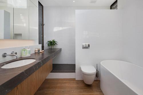 a bathroom with a sink and a toilet and a tub at Newton Heights in Akaroa