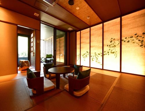 Balinese onsen ryokan Hakone Airu في هاكوني: غرفة معيشة مع طاولة وكراسي ونافذة