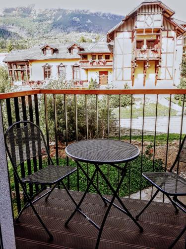 a table and chairs on a balcony with a house at 4Roses Apartments in Smokovce