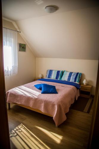 a bedroom with a bed with blue sheets and a window at Apartmani Huško in Tuheljske Toplice