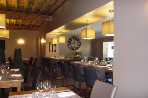 a restaurant with tables and chairs and a clock at Logis Hôtel Burnichon in Tarare