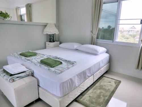 a white bedroom with a large white bed and a window at Green View 104 Khao Kho in Khao Kho