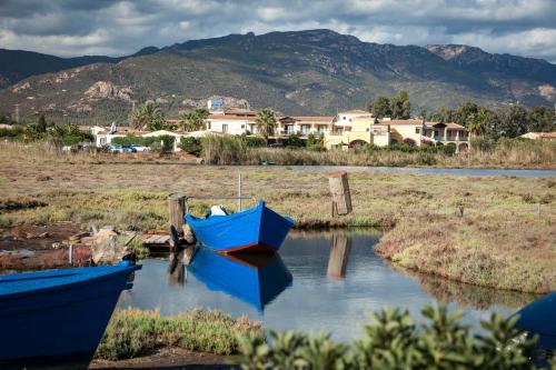 two boats in the water with houses in the background at Hotel Santa Gilla in Capoterra