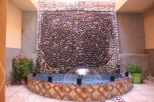 a fountain in a lobby with a large stone wall at Dar Imperial in Imlil