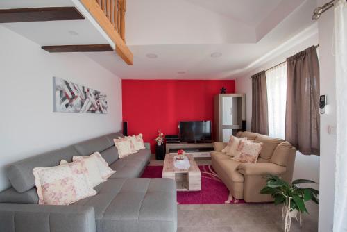 uma sala de estar com um sofá e uma parede vermelha em Villa Ivana em Zagvozd