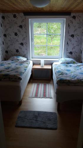 ハーグフォシュにあるStuga Hultの窓とラグ付きの部屋のベッド2台
