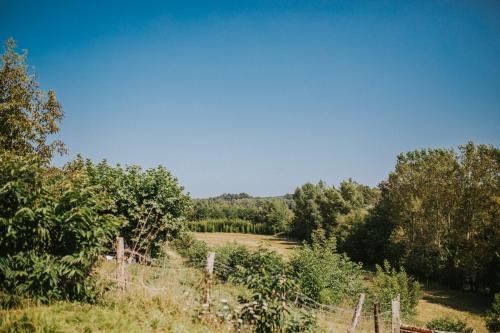 a field with a fence and trees in the background at Maison de la riviere in Autevielle-Saint-Martin-Bideren