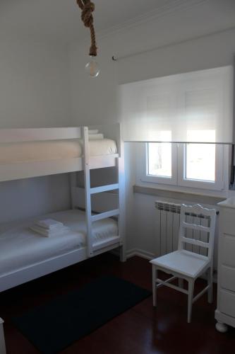 sypialnia z 2 łóżkami piętrowymi i krzesłem w obiekcie HappySintra GuestHouse by Casa do Preto w mieście Sintra