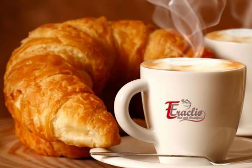 uma chávena de café e um croissant numa mesa em B&B Eraclio Suite em Barletta