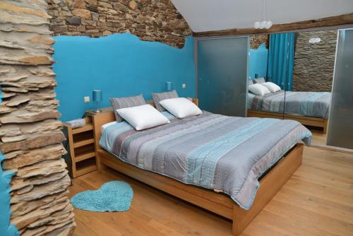 a blue bedroom with a bed and a stone wall at Gîte Au Coeur de Champlon in Champlon
