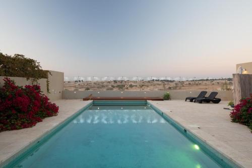 a swimming pool with two chairs and a view of the desert at DesertB in Giv'ot Bar