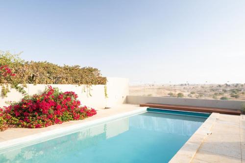 a swimming pool with flowers and a view of the desert at DesertB in Giv'ot Bar